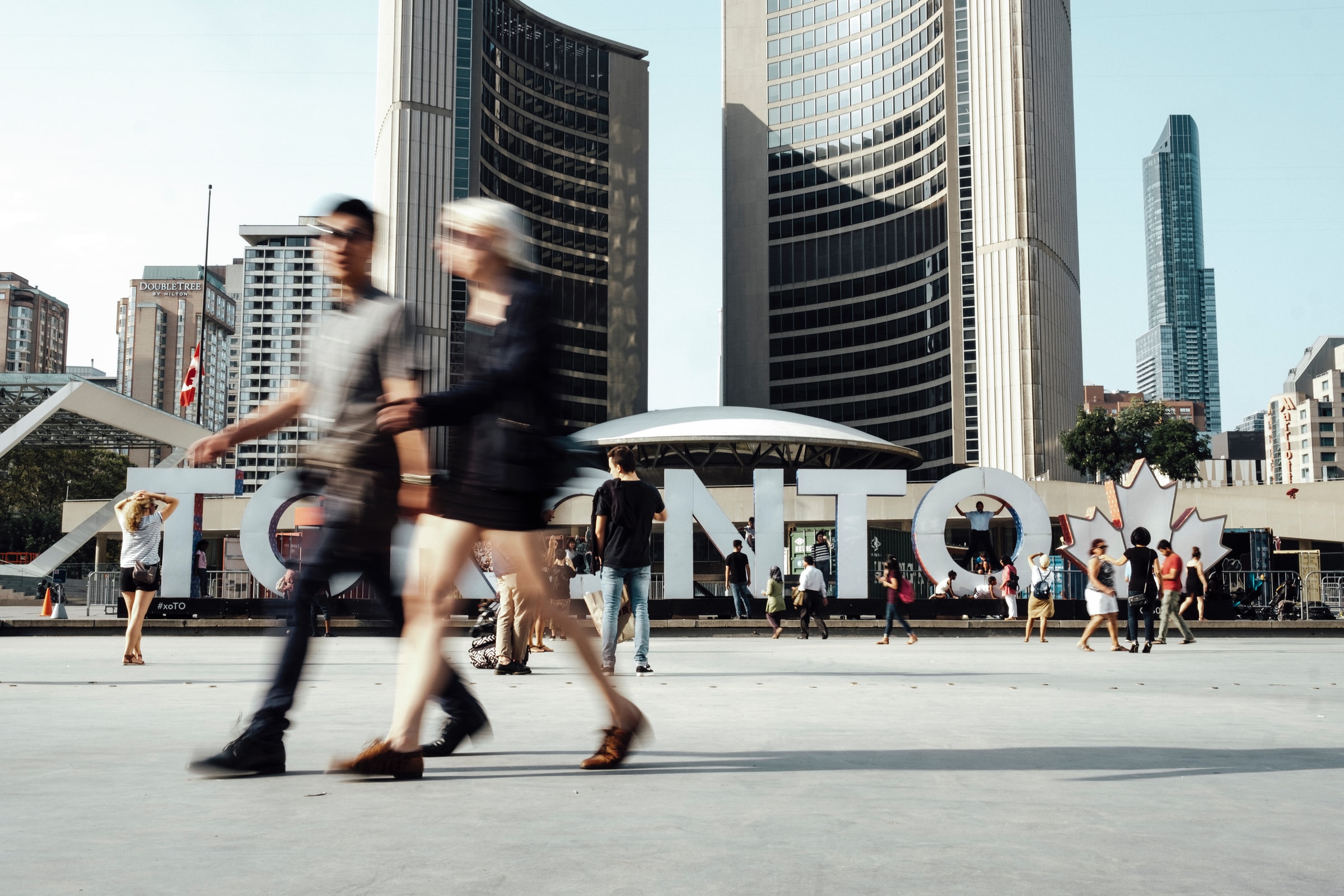 People walking across a sign that says Toronto.